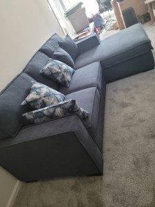 The couch is closed to the normal size with an ottoman at one end.